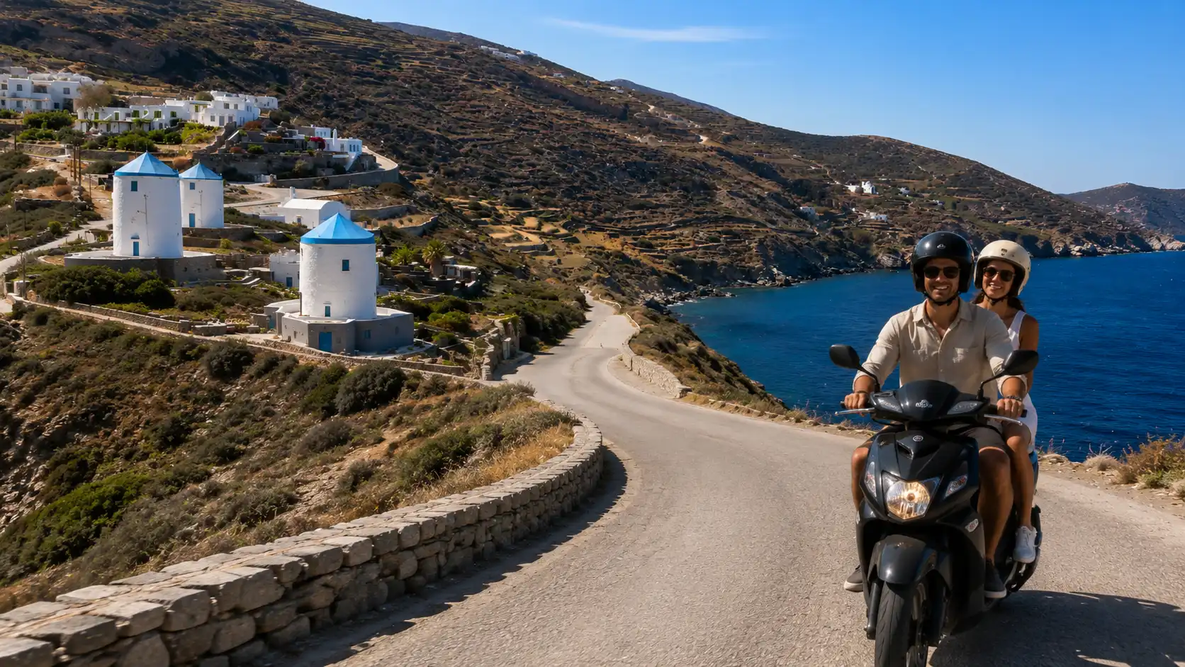 Couple riding a scooter past the windmills of Sifnos